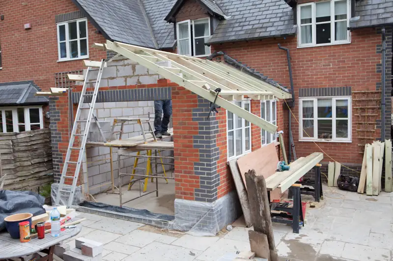 Blockwork house extension under construction with a timber roof frame